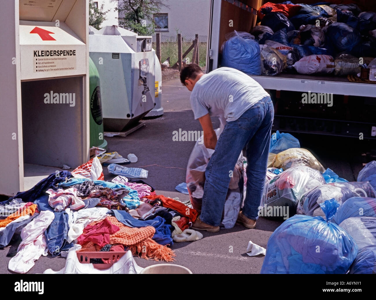 man emptying a container for collecting old used clothes Stock Photo