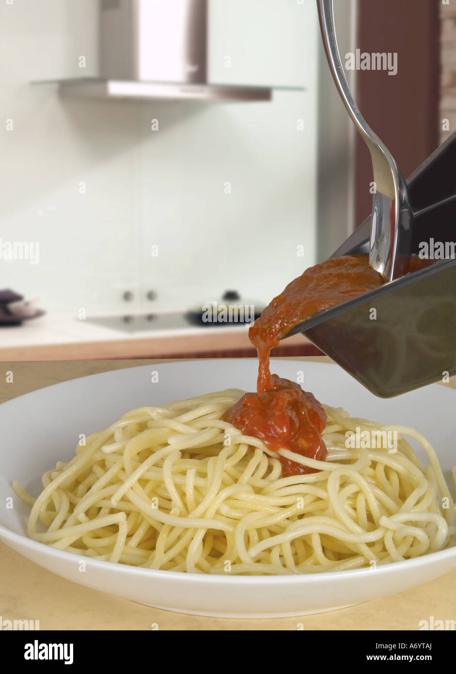 Pouring Bolognese sauce over spaghetti Stock Photo