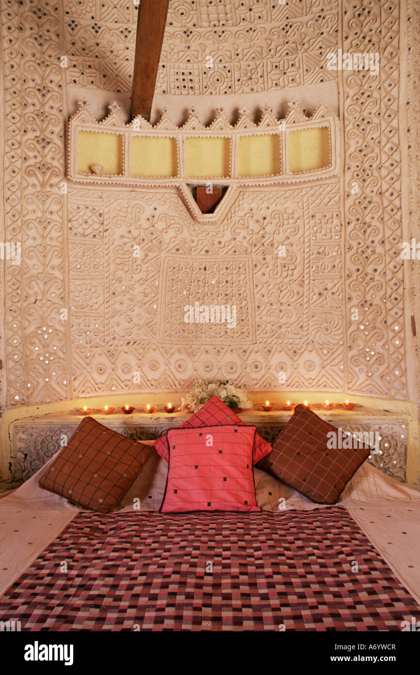 Raised mud reliefs inlaid with mirror on the walls of bedroom in modern home in traditional tribal Rabari round mud hut Bunga Stock Photo