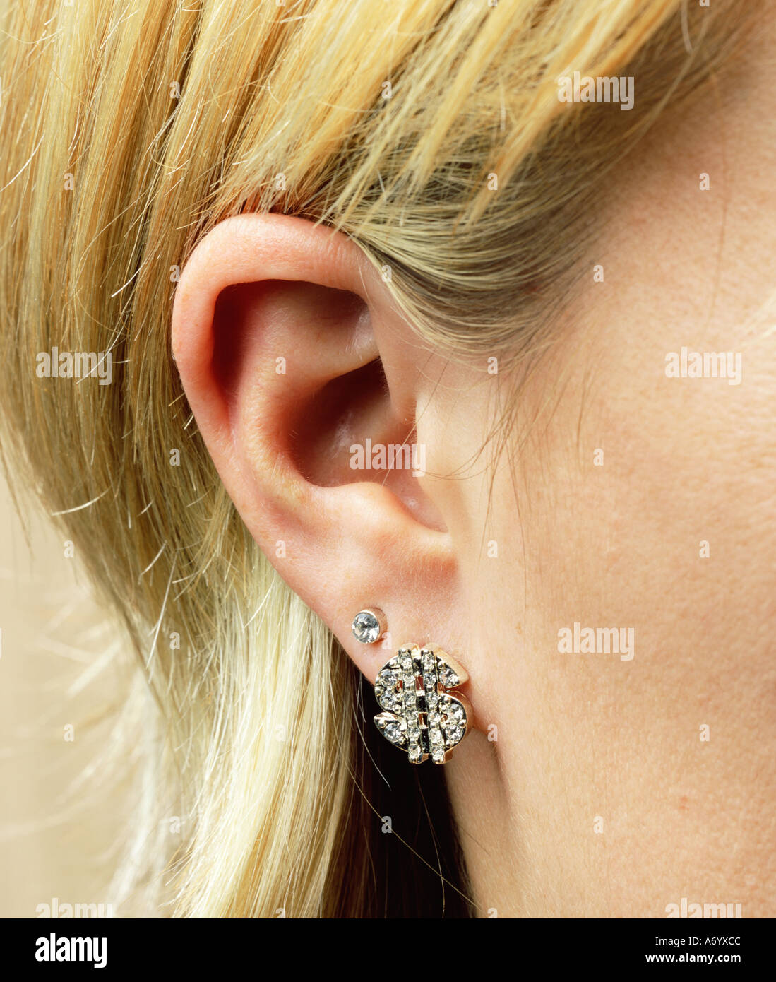 Dollar earring on woman s ear Stock Photo