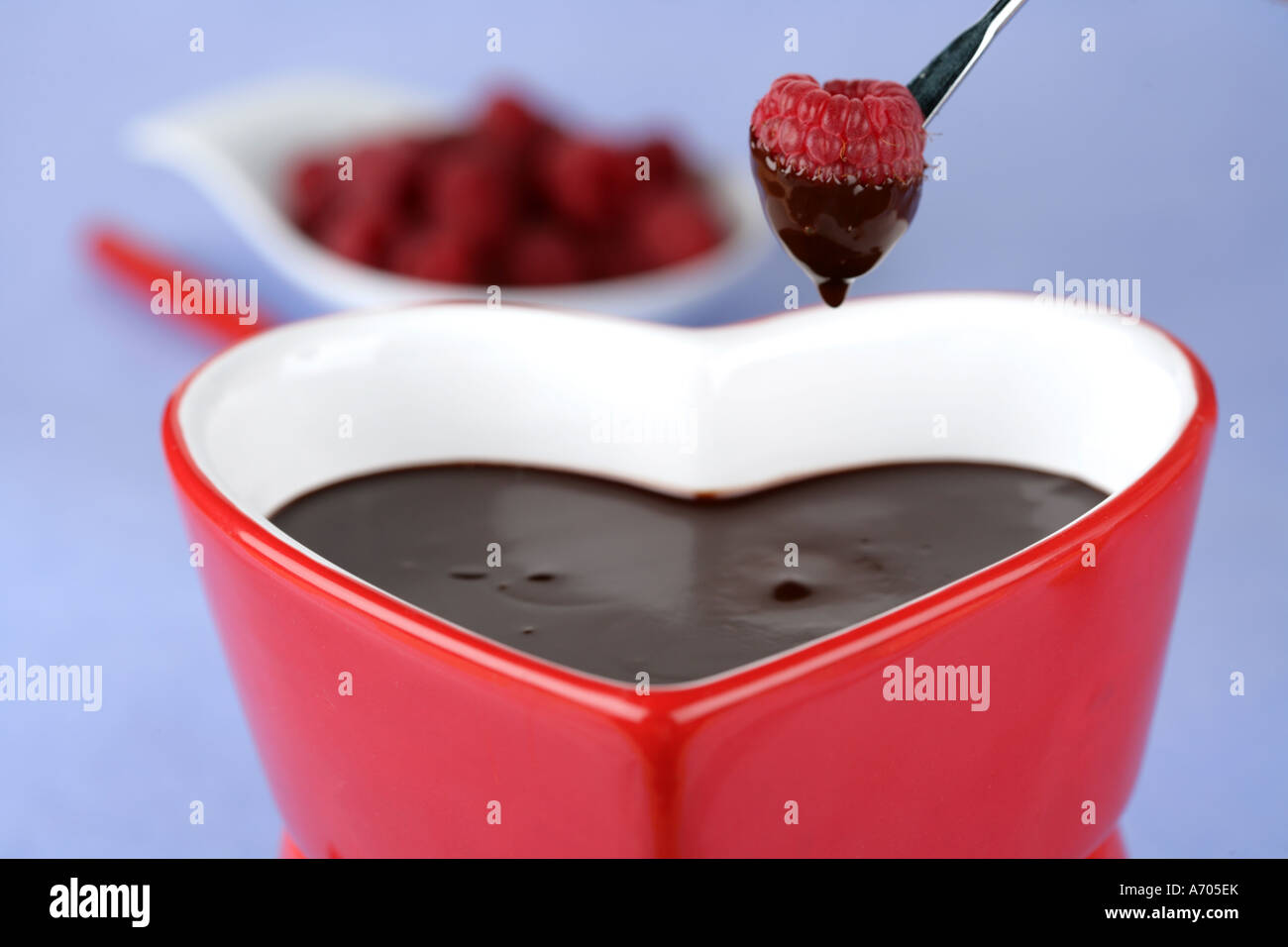 Heart shaped chocolate fondue dipping a raspberry Stock Photo Alamy