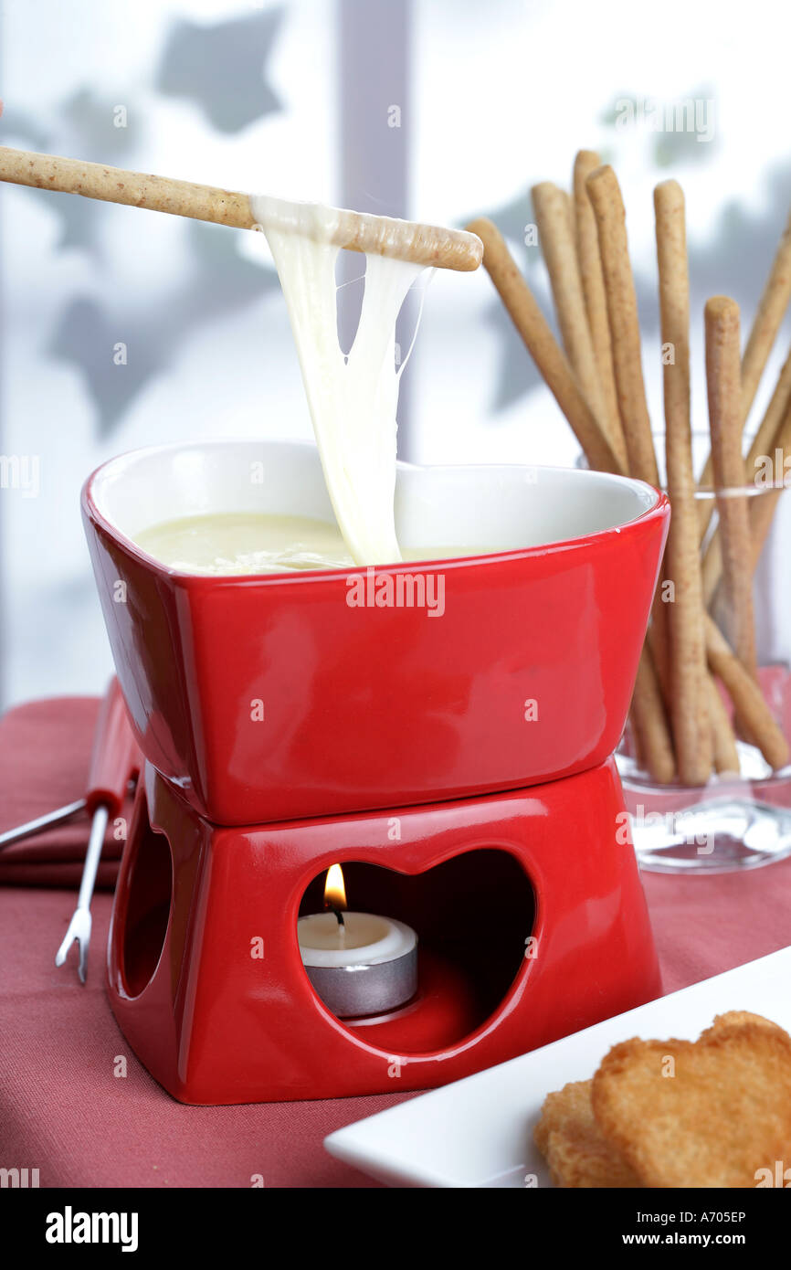 Dipping bread sticks in cheese fondue Stock Photo Alamy