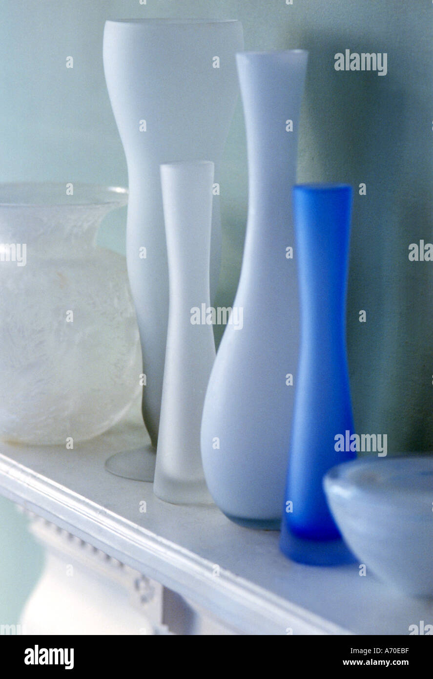Collection of white bluefrosted glass vases on mantel shelf Stock Photo