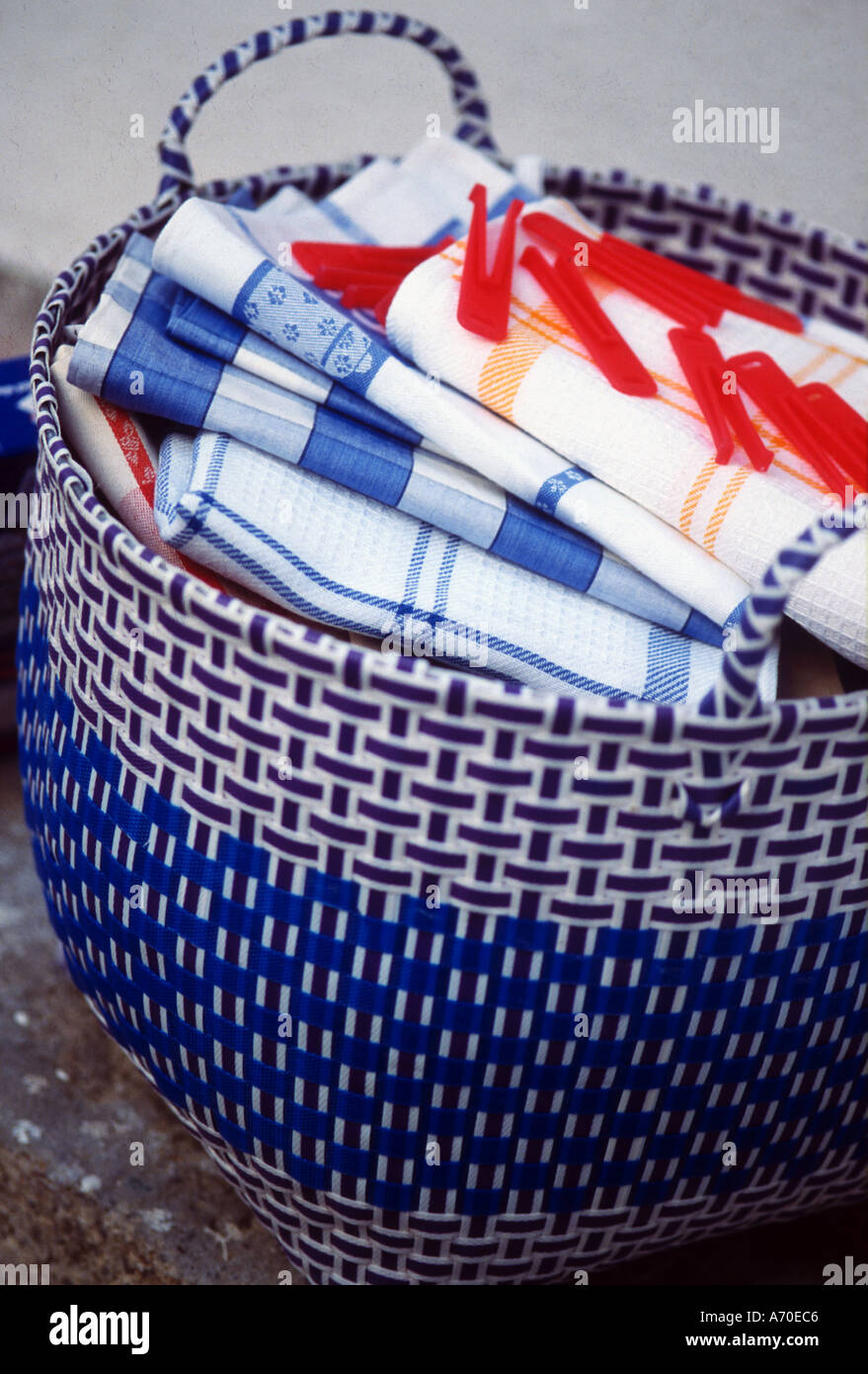 Laundry basket woven in coloured plastic filled with carefully ironed