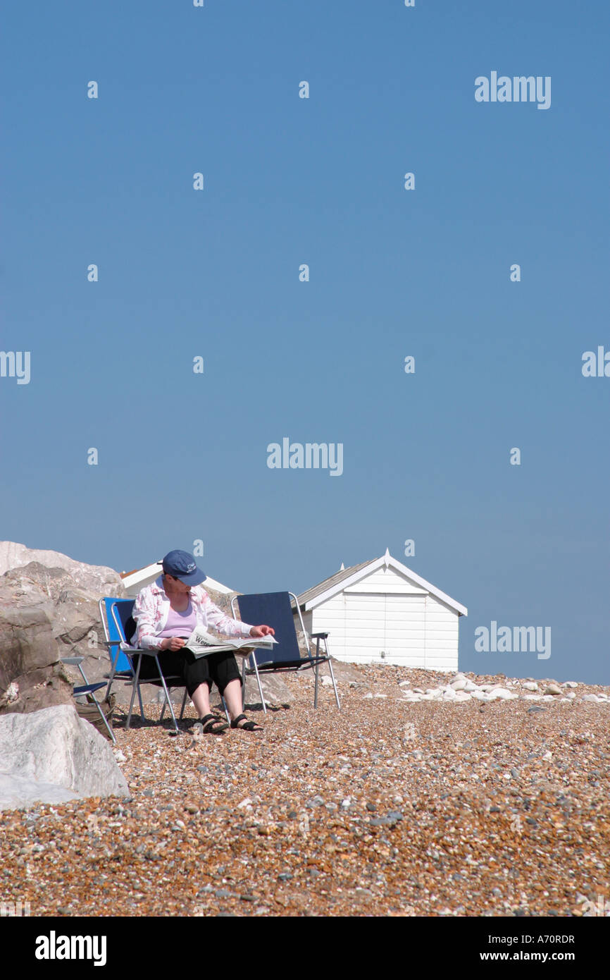 Middle aged lady reading newspaper on beach at GoringbySea, West