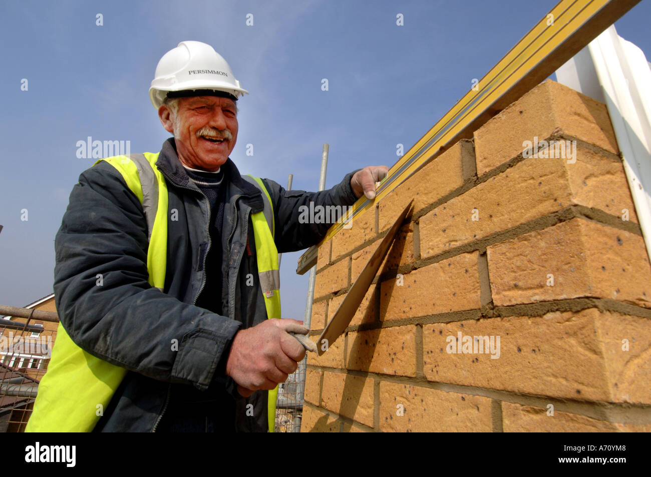Experienced older bricklayer laying bricks on a housing development Stock Photo