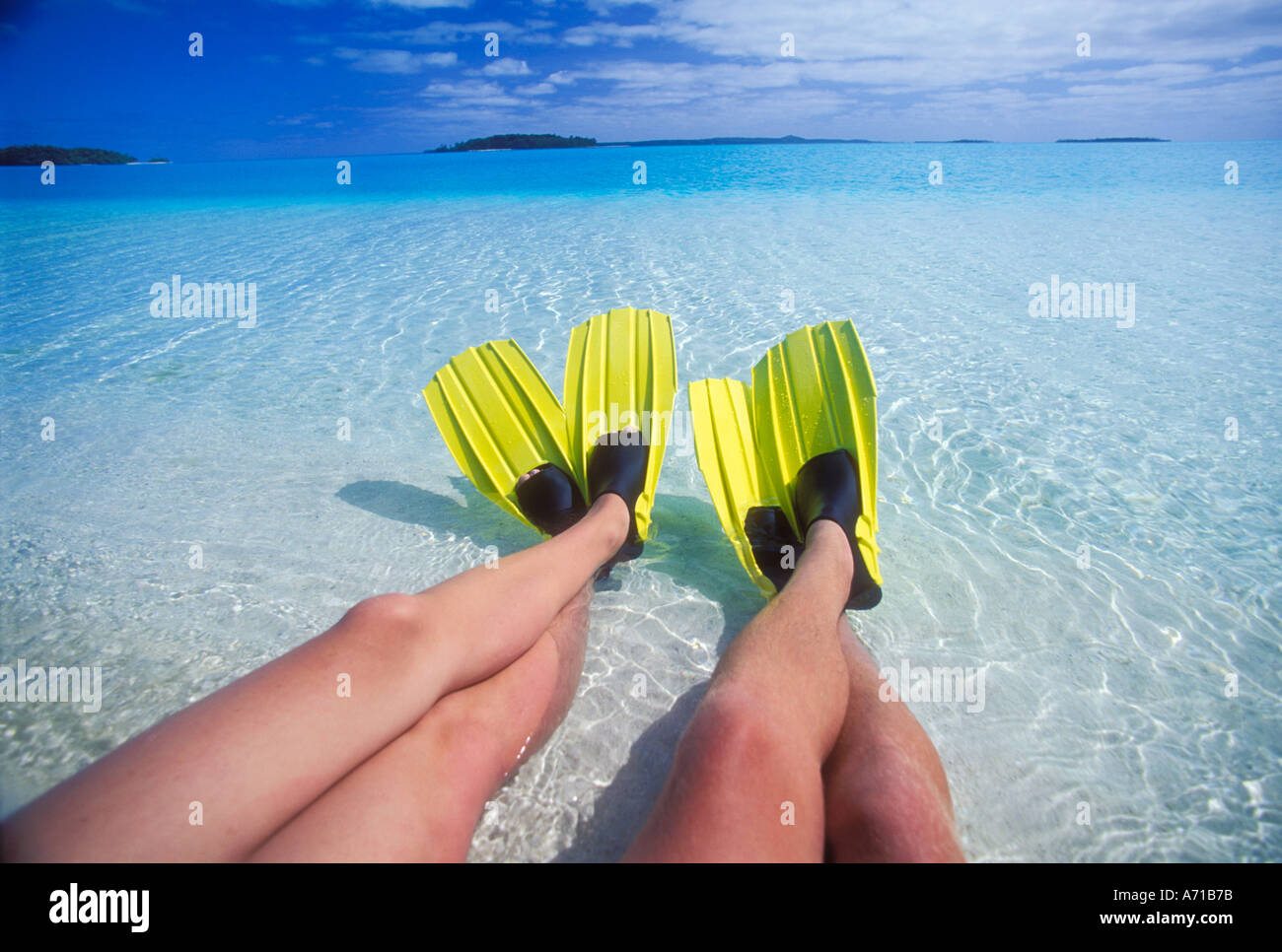 Two pair of legs with yellow swim fins on feet Aitutaki Lagoon Cook Islands South Pacific Ocean model released image Stock Photo