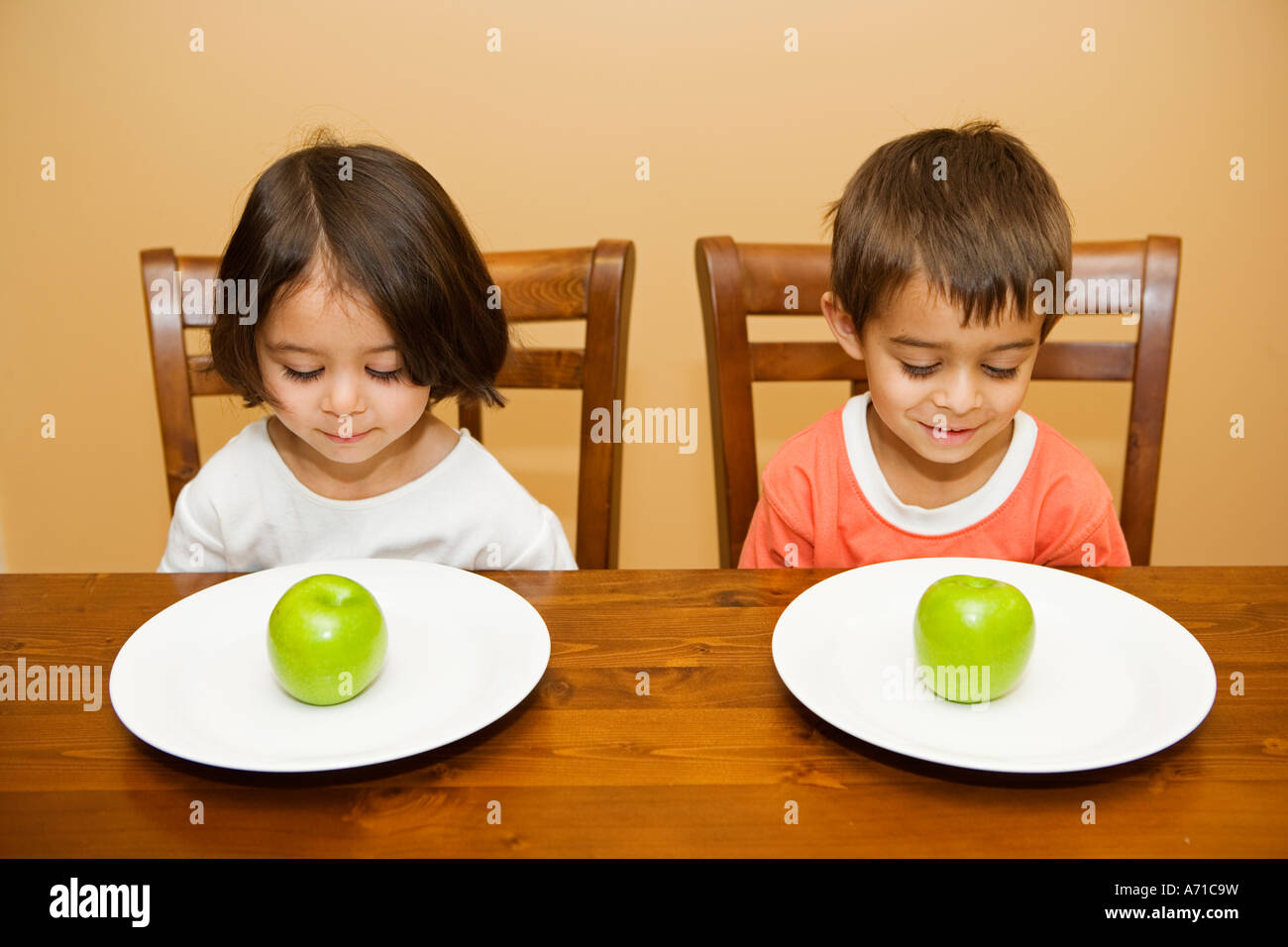 Boy and girl at table with apples on plates Stock Photo