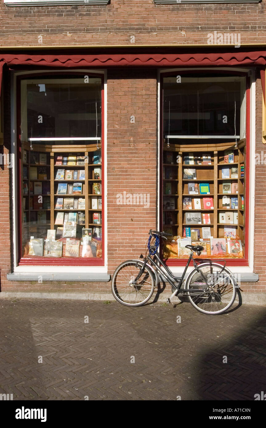 Black bicycle parked on a brick sidewalk outside a book shop window display in Utrecht, Holland. Charming street scene in the Netherlands. Stock Photo