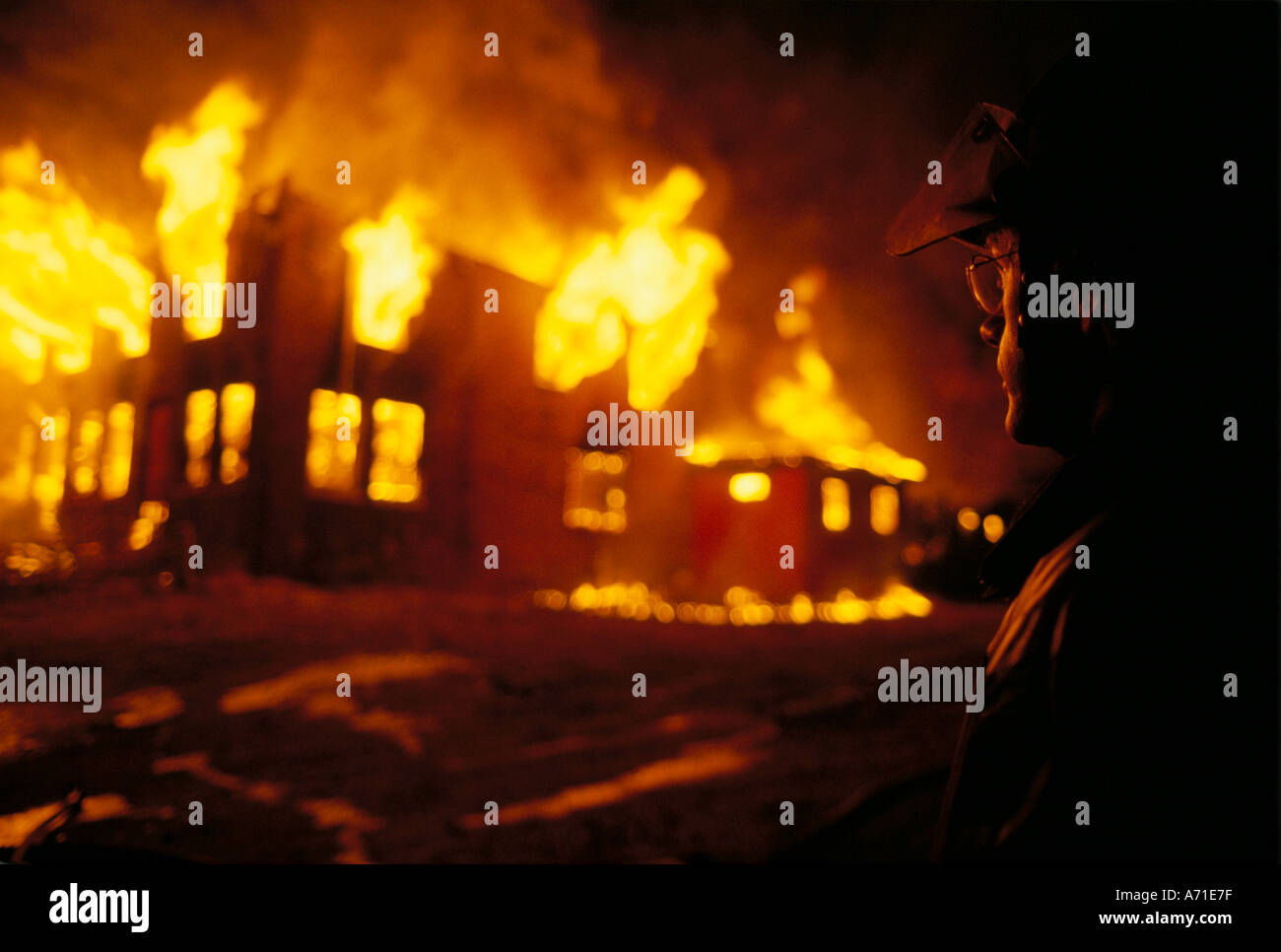 Side profile of a fireman overseeing a disasterous fire in a building Stock Photo