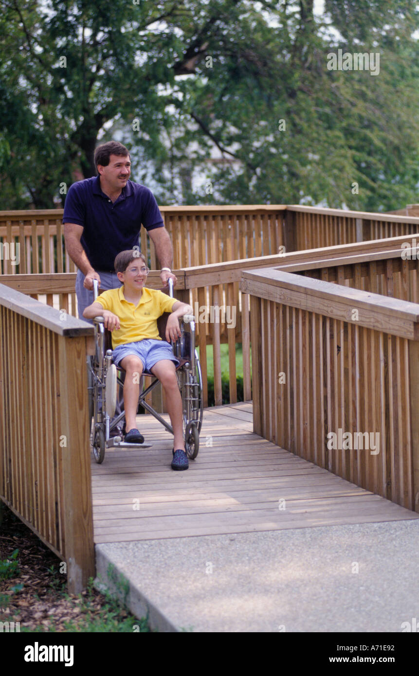 Man helping boy in wheelchair down a ramp in Handicapped Park in