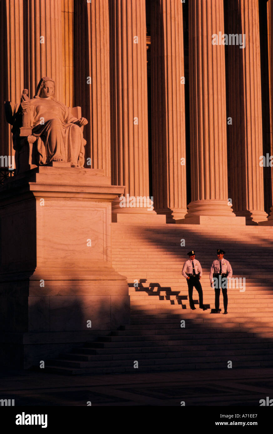 Two uniformed policemen standing on the steps of U Supreme Court building in the light of a sunset Washington D C Stock Photo