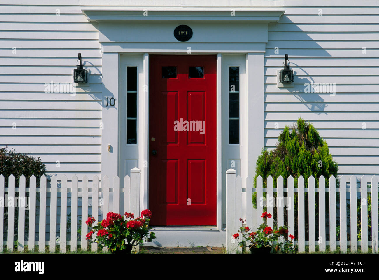 Close Up Of A Red Front Door Of A White Frame House With Flowers