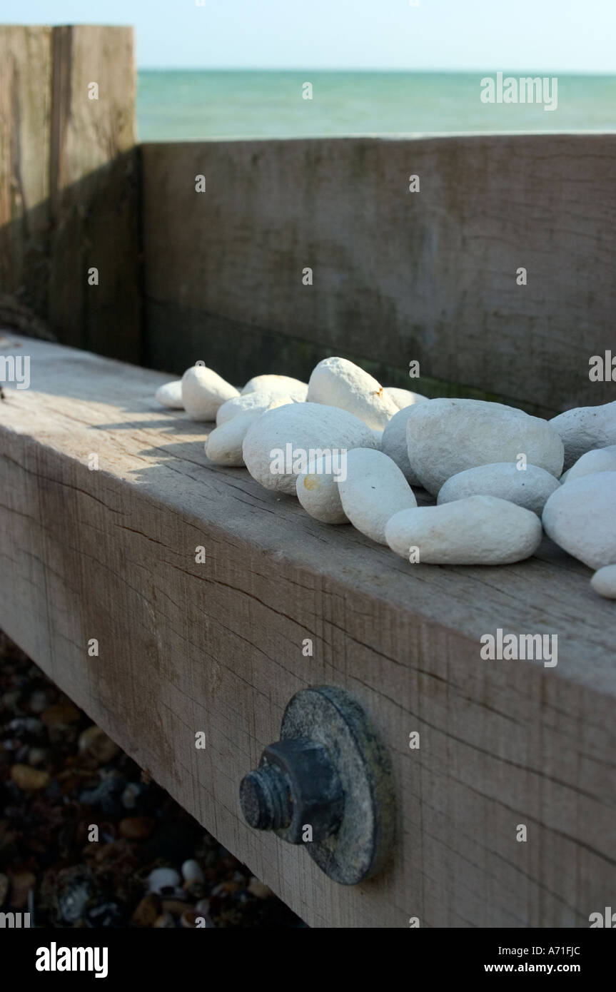 Wooden sea defence structure with gathered white pebbles. Stock Photo