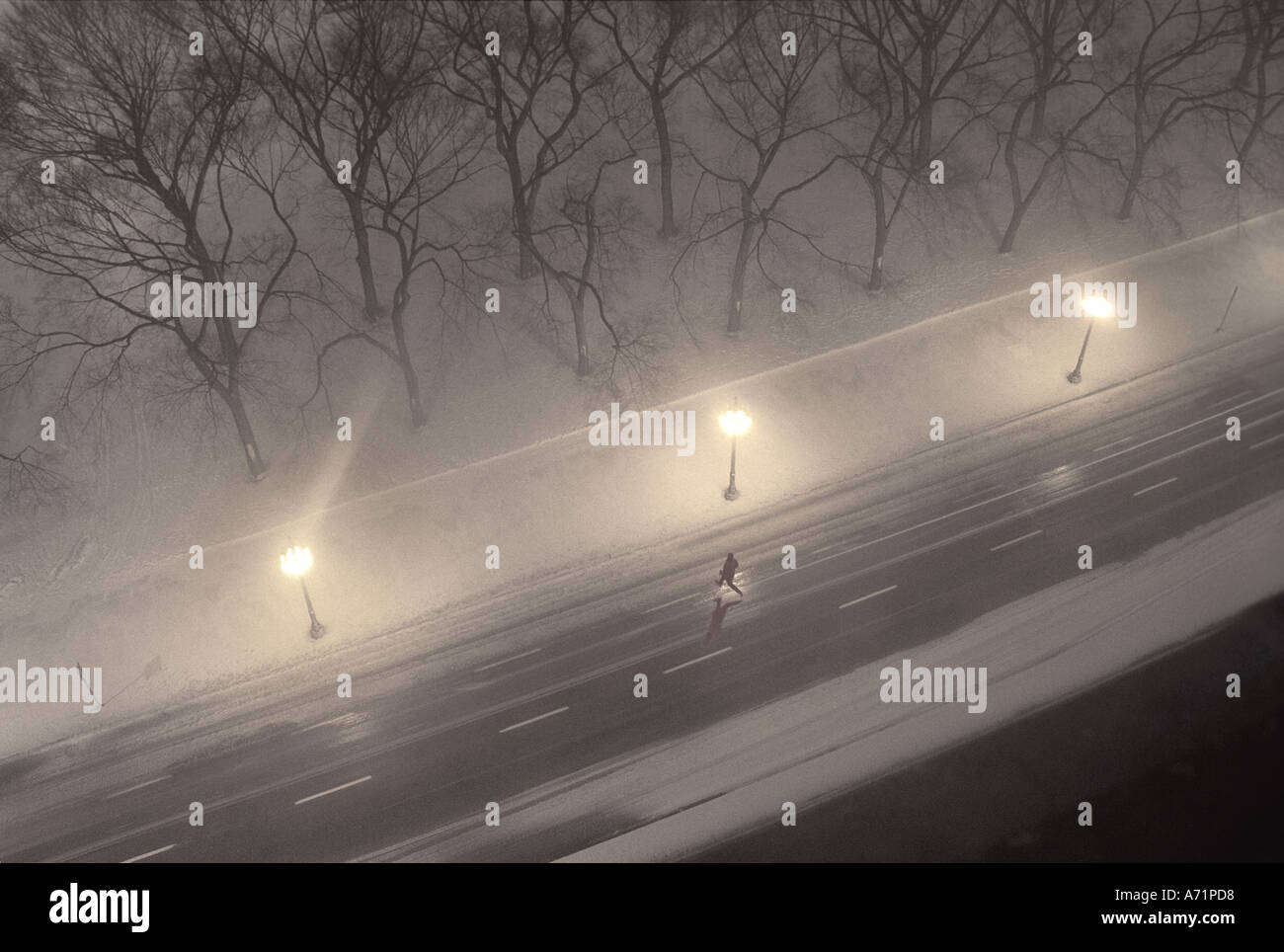 Man running across street, jumping over puddle in winter snowstorm, Chicago USA Stock Photo