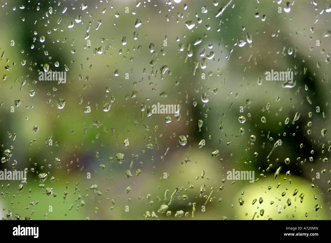 a water droplet covered window with a green garden behind it Stock Photo