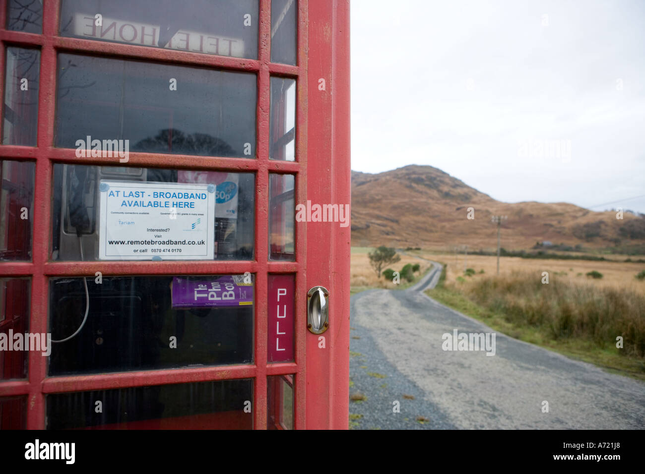 Red British telephone box in remote rural area with sign advertising ...