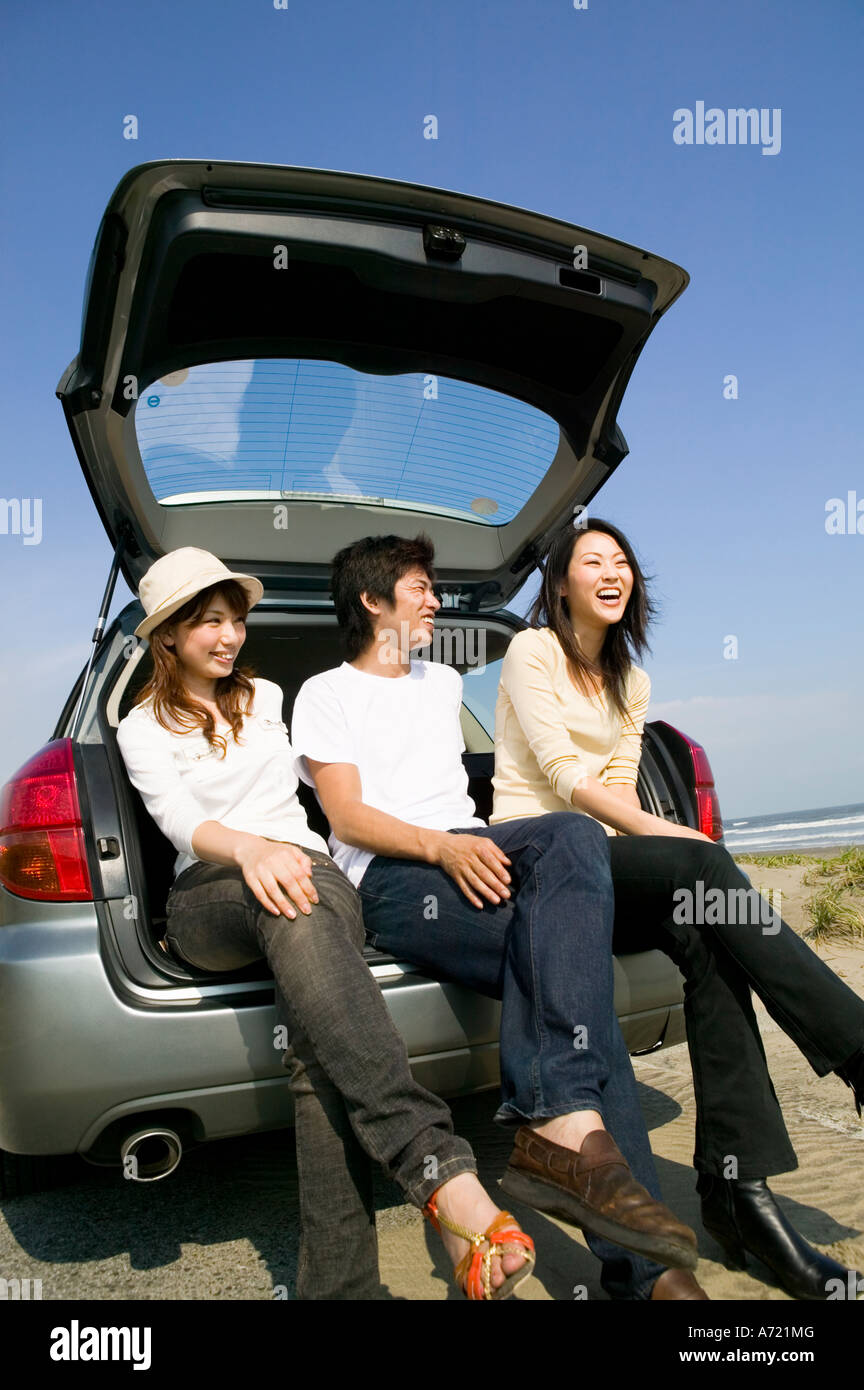 Young people sitting on rear of car Stock Photo