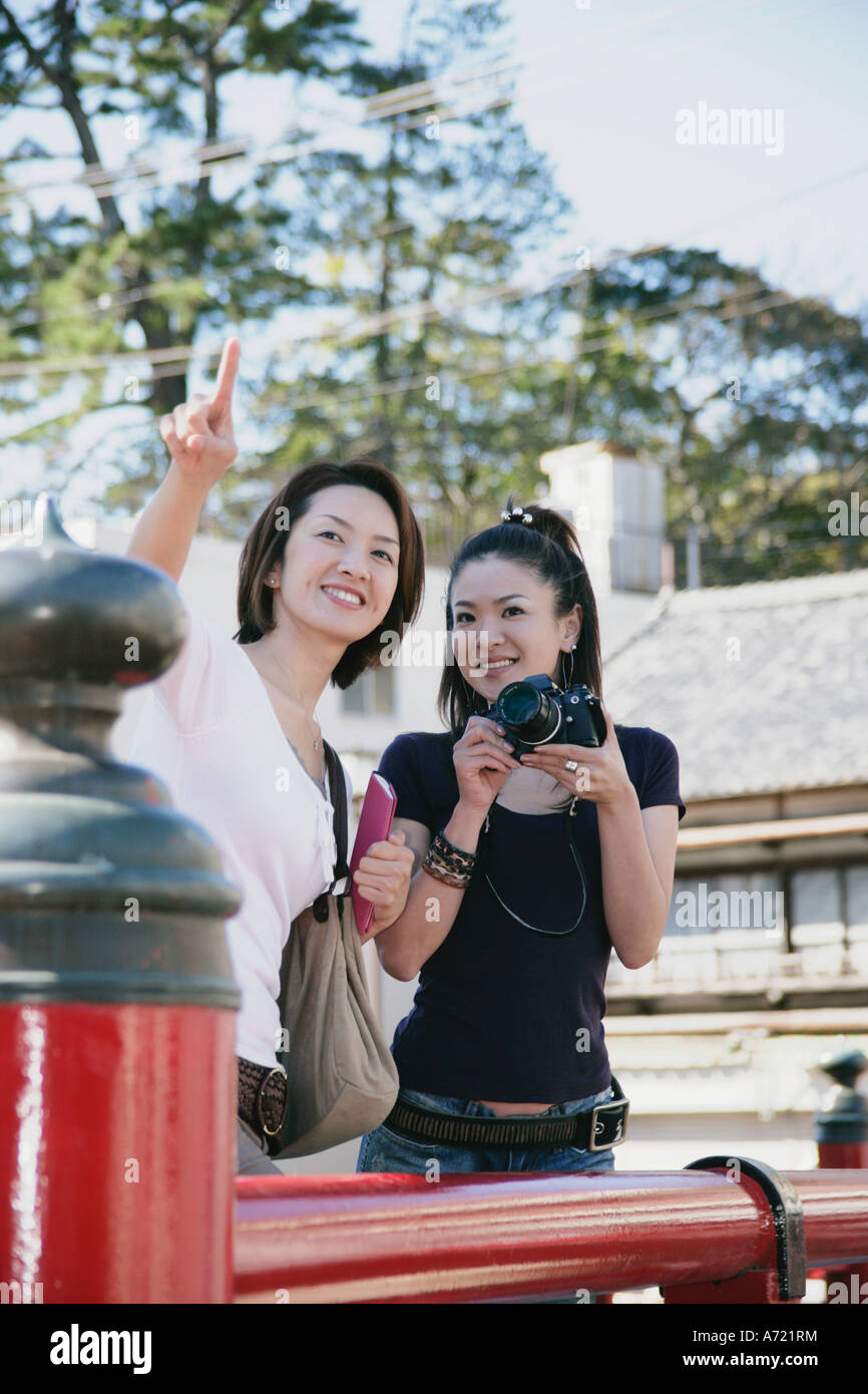 Two young women standing on bridge, one with camera Stock Photo - Alamy