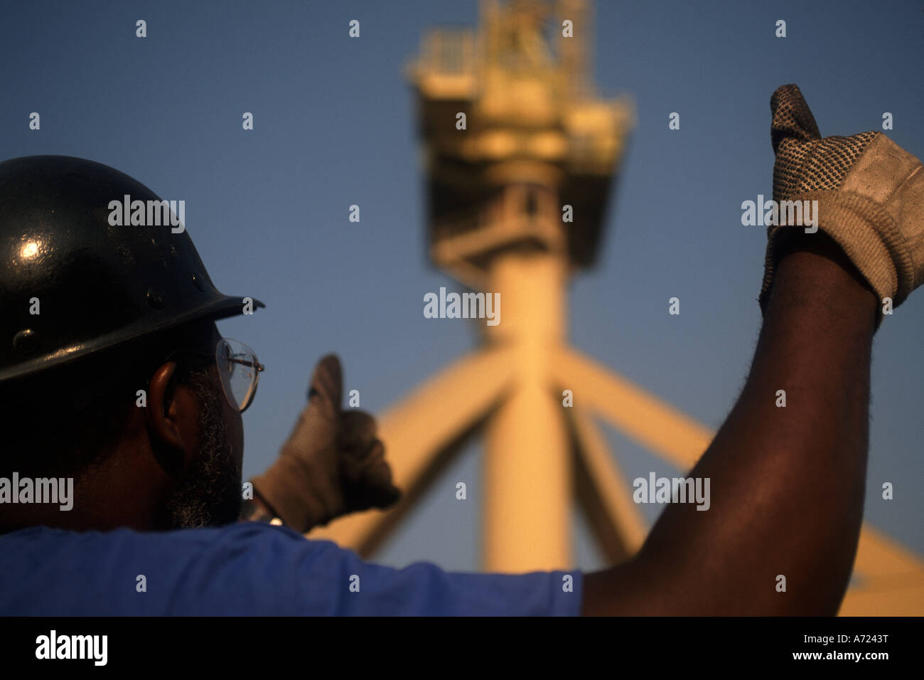 An african american construction worker uses his thumbs to signal a crane operator. Stock Photo