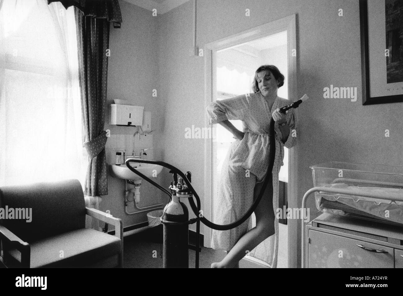Gail taking gas and air for pain relief after 12 hours of labour standing to let gravity assist with the labour . Stock Photo