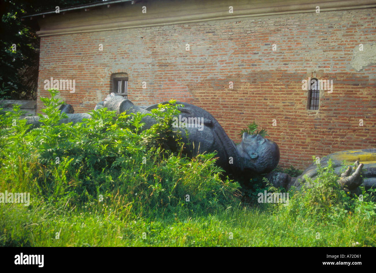 Fallen statute of Lenin in weeds behind wall outside Bucharest in Romania Stock Photo