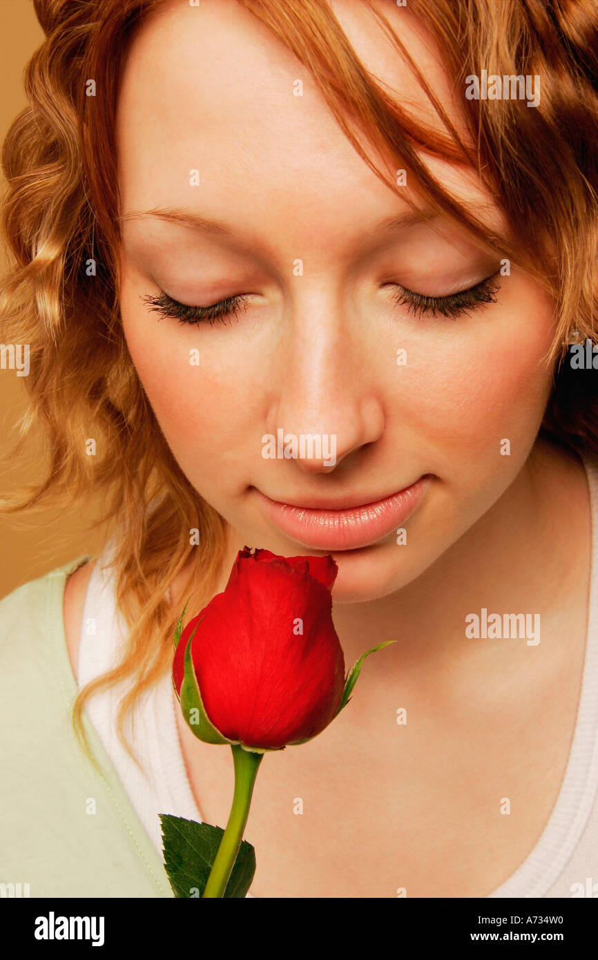 A young adult smelling a red rose Stock Photo - Alamy