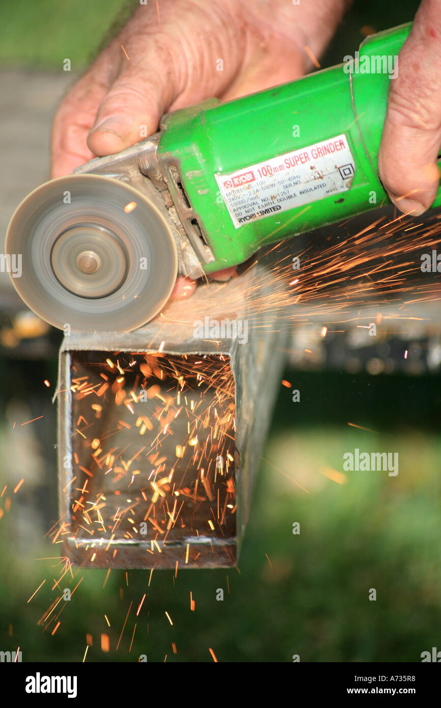 Cutting steel with an angle grinder showing sparks spraying out Stock