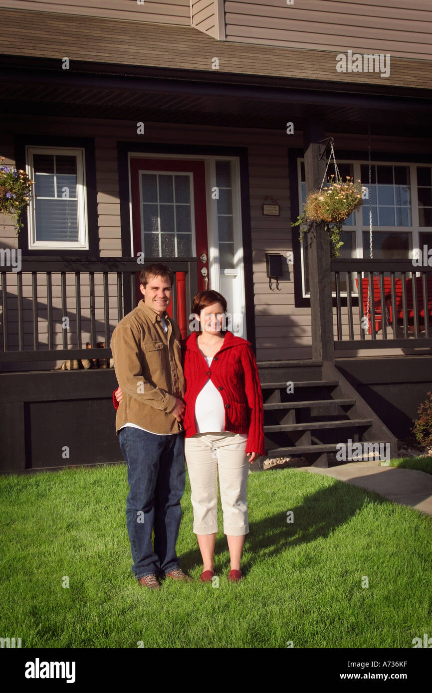 Couple standing in front of new house Stock Photo - Alamy