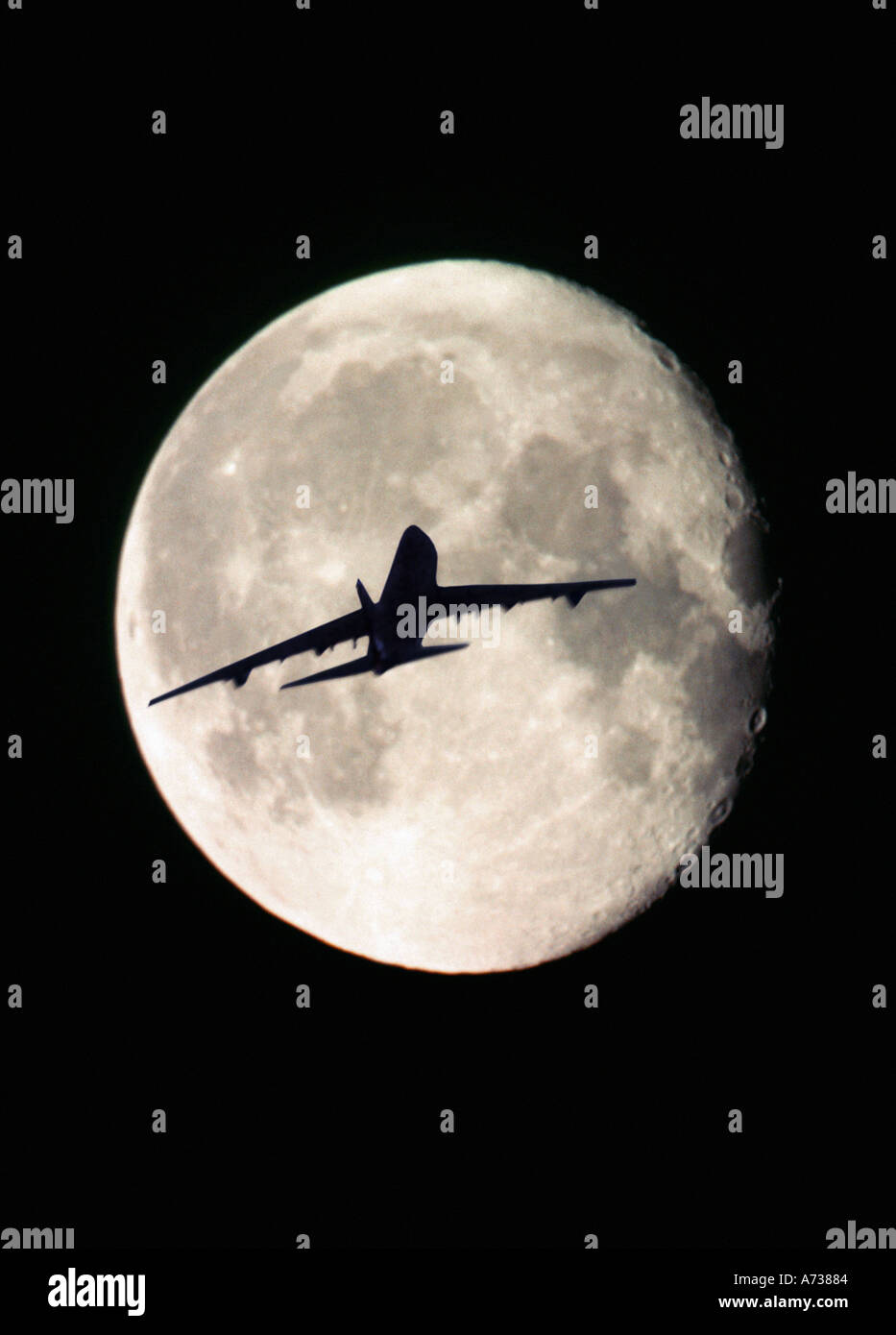 jet plane flying across the disc of the moon Stock Photo