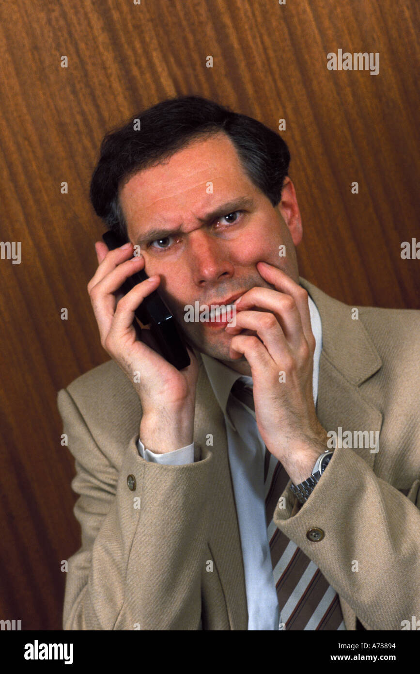 businessman on mobile phone looking under pressure Stock Photo