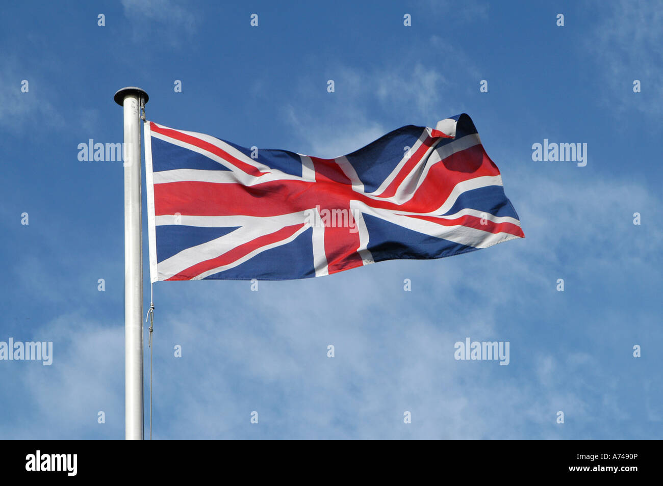 Union jack flag fluttering in the wind against a blue sky Stock Photo ...