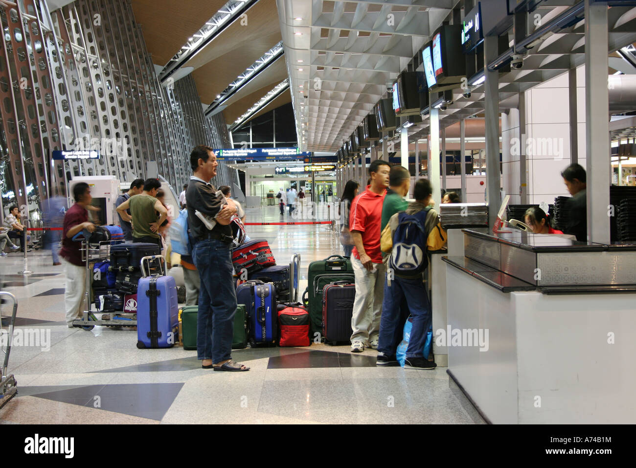 Travellers at Kuala Lumpur International Airport queueing to weigh their luggage at check-in counter. Stock Photo