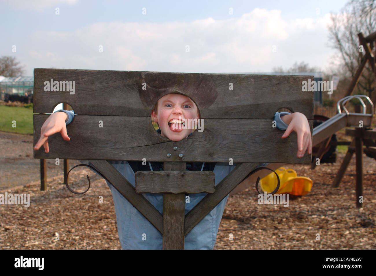 Boy Fooling About In Wooden Stocks. Stock Photo