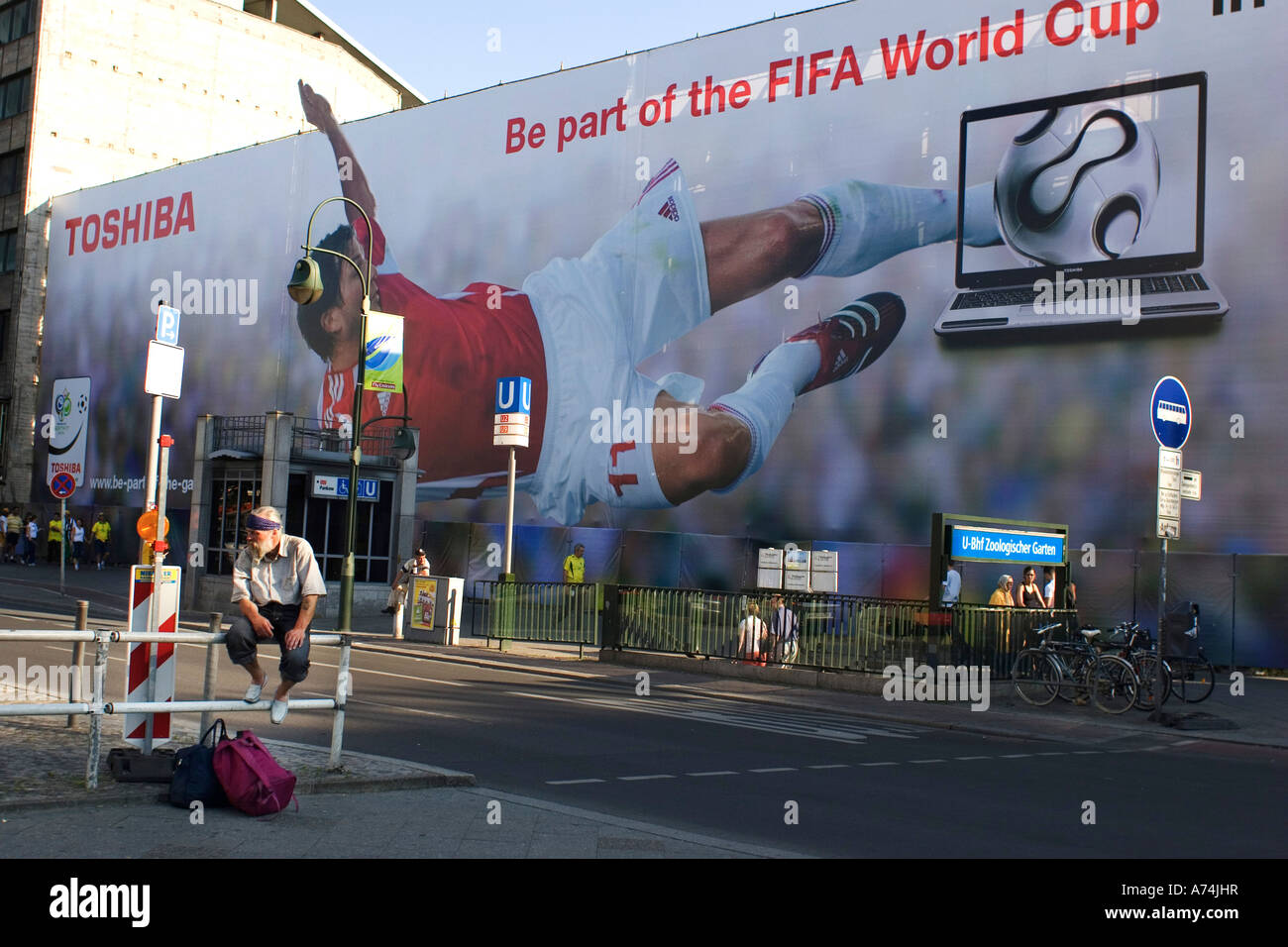 A man resting in Berlin possibly homeless in  front of World Cup billboard Summer 2006 Stock Photo