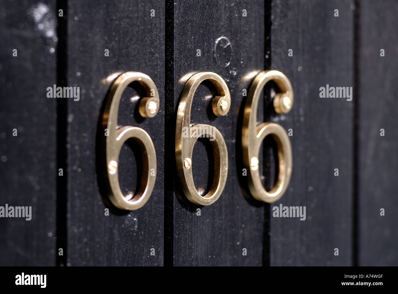 Brass door number 666 on a black wooden door Stock Photo