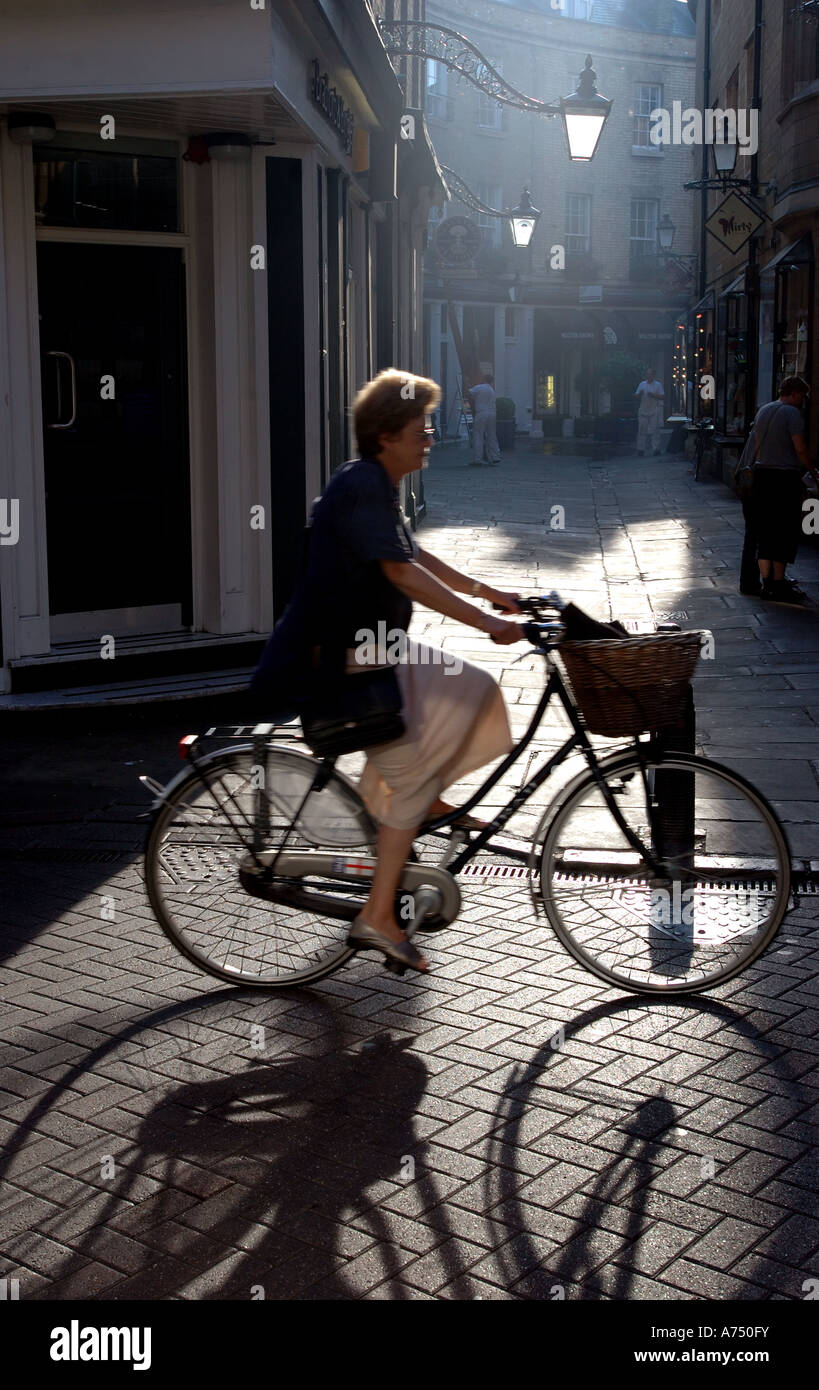 Strong back lit image of a woman riding an old fashioned bicycle with