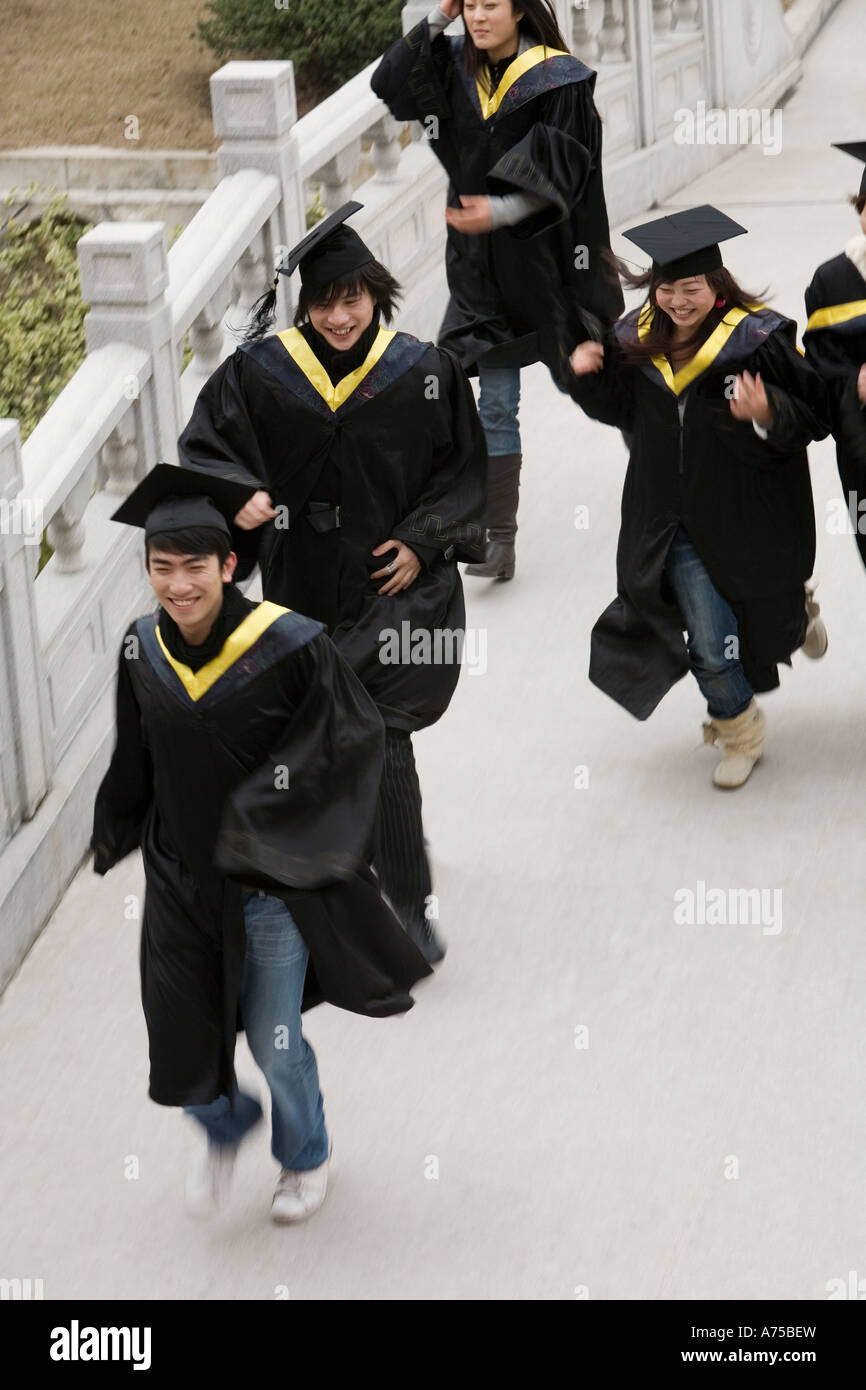 Students in graduation robes running Stock Photo Alamy