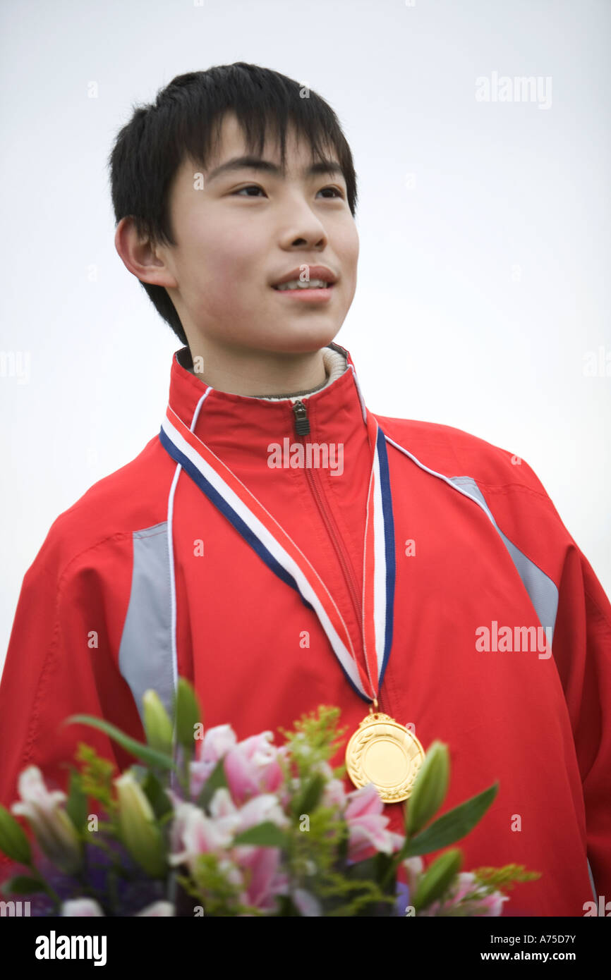 Male athlete wearing a gold medal and holding flowers Stock Photo - Alamy