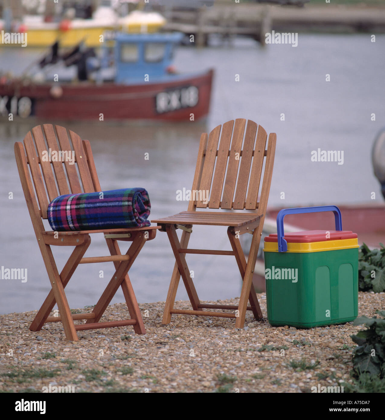 Folding wooden chairs with plastic picnic box and folded tartan rug on