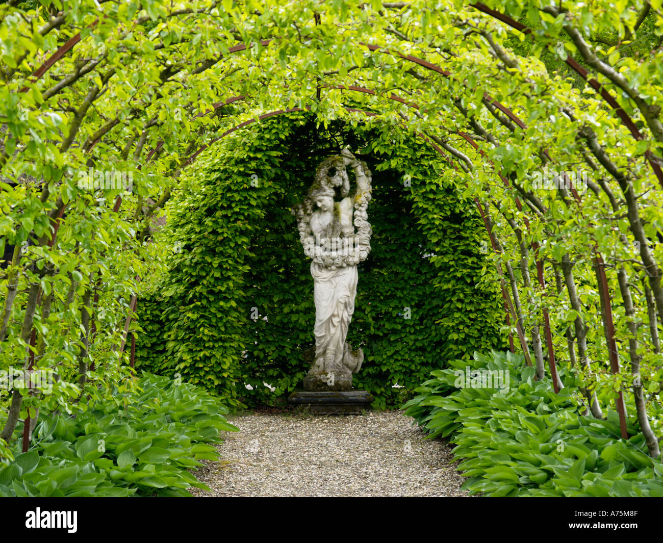 Beautiful garden with curved pergola and stone statue of a female figure Arnhem the Netherlands Stock Photo