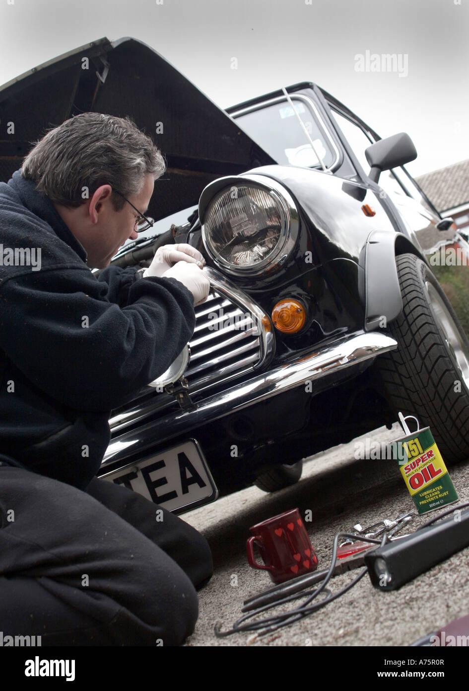 A HOME MECHANIC WORKS ON A CLASSIC ROVER MINI CAR.UK Stock Photo