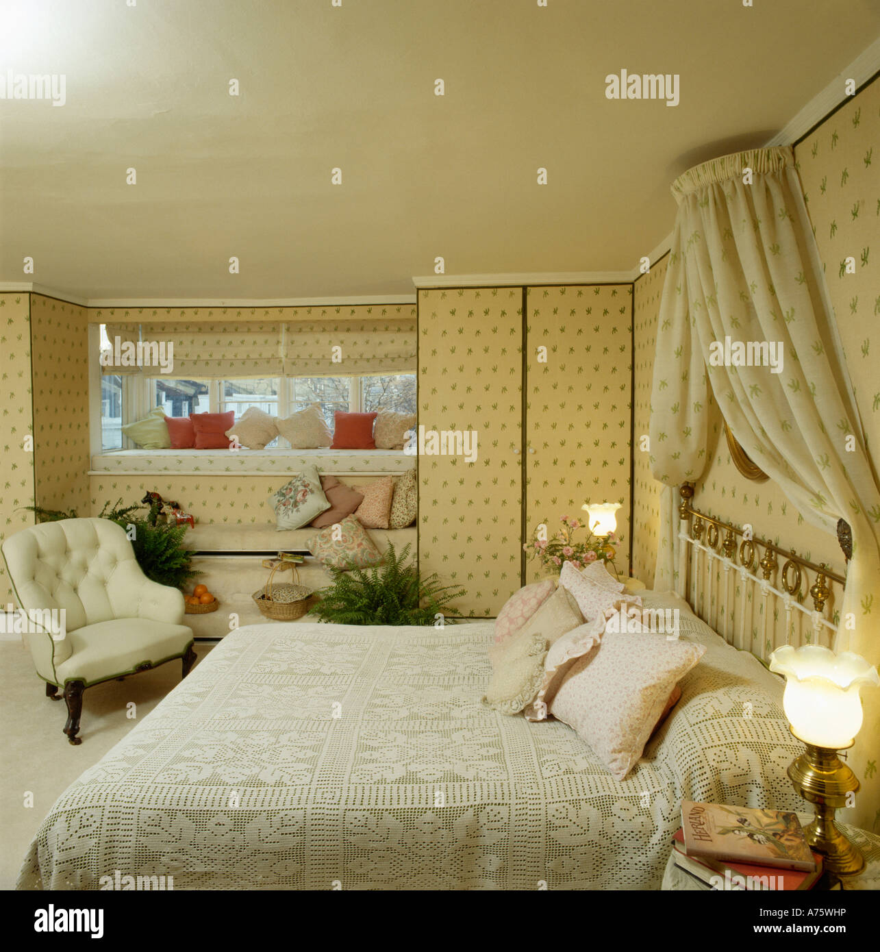 drapes above bed with lace bedlinen in bedroom with wallpaper and lighted lamps beside