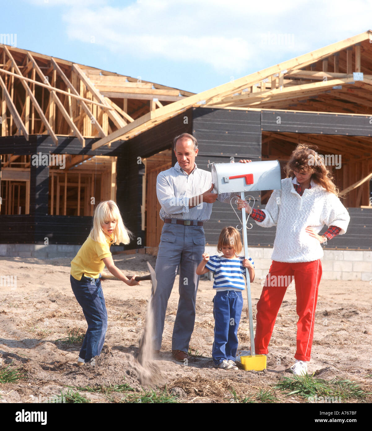 family of four putting up mailbox in front of house under construction Stock Photo