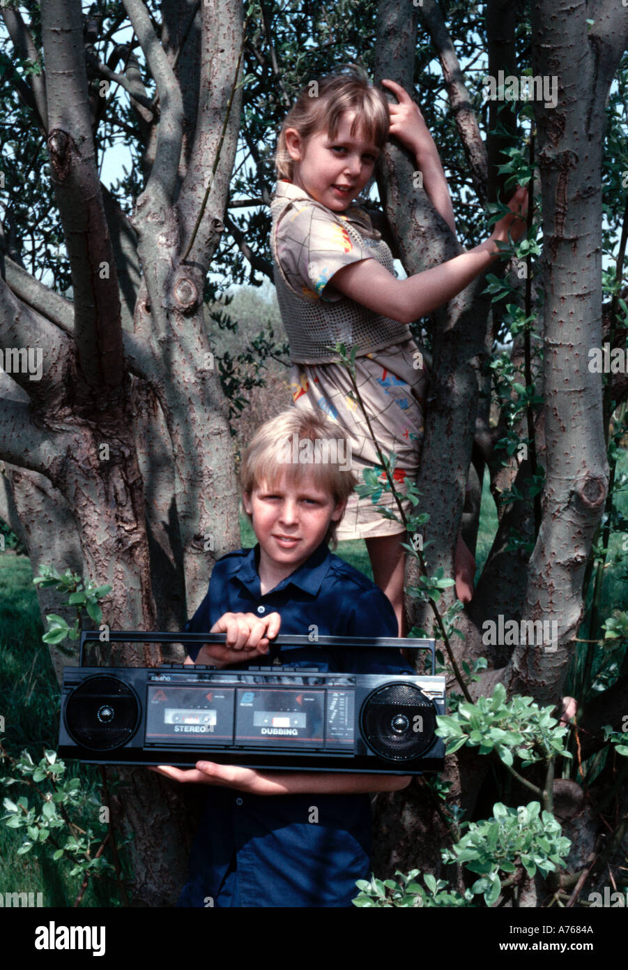 Two children in a tree with a ghetto blaster 1980s Stock Photo