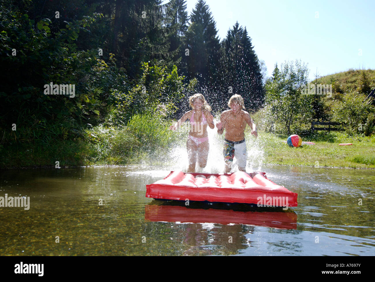 Young couple jumping on air mattress Stock Photo Alamy