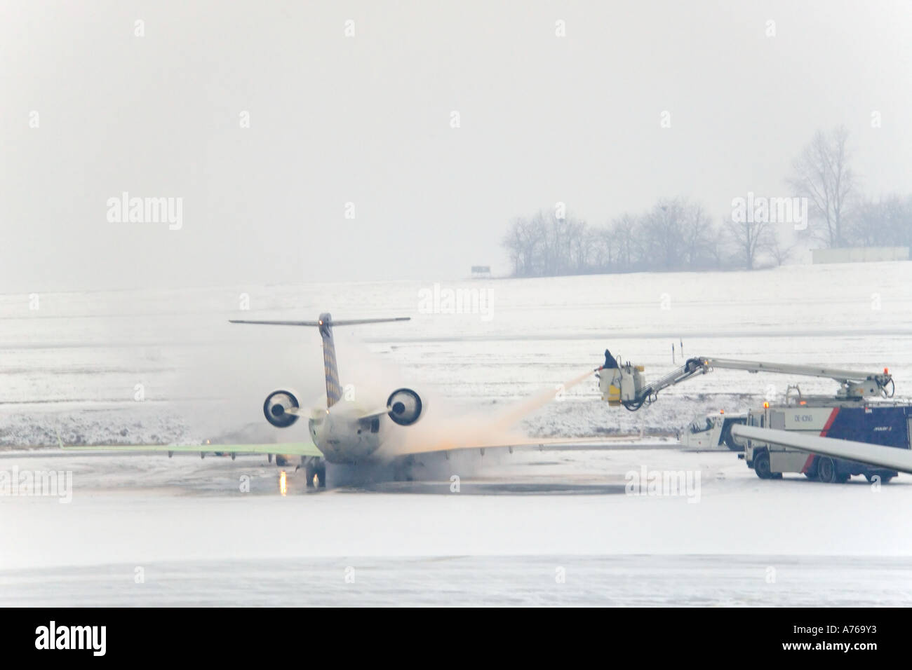 The view from an aircraft window of workers de-icing the planes prior to take off. Stock Photo