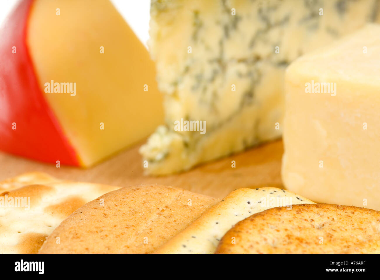 Chunks of Edam, Stilton and cheddar cheeses with biscuits on a cheese board. Stock Photo