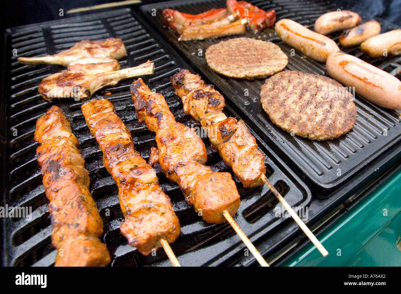 Selection of different meats and kebabs sizzling on a BBQ Stock Photo