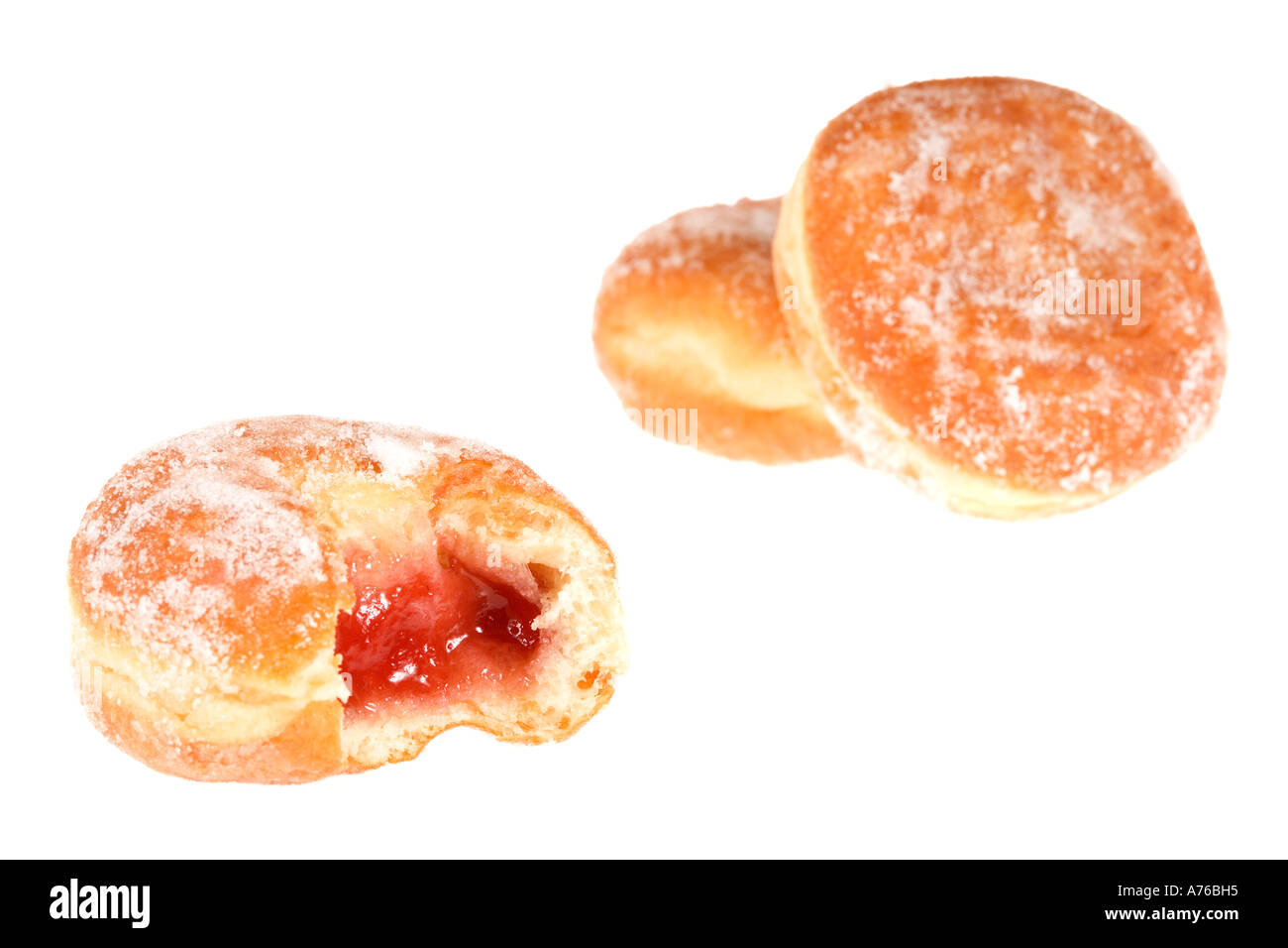 Three jam doughnuts one bitten into exposing the jam on a pure white background. Stock Photo